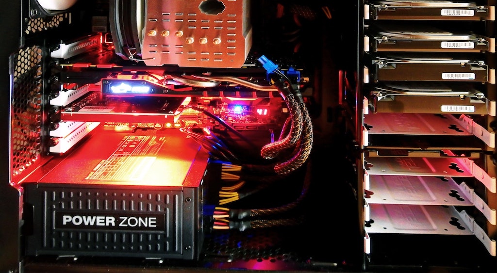 Computador visto de dentro. Iluminação em led vermelho e componentes como fonte e cpu à mostra.