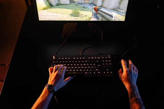 Homem jogando video game utilizando um teclado e mouse gamer.