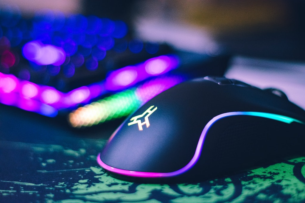 Mouse gamer preto com leds coloridas visto de perto.