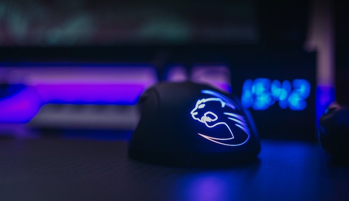 Mouse gamer preto com leds azuis em ambiente escuro.