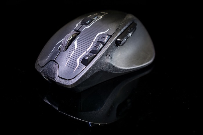 Mouse gamer cinza em superfície e fundo completamente pretos.