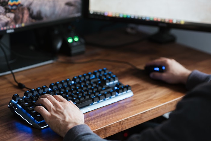 Homem utilizando um mouse gamer e um teclado gamer.