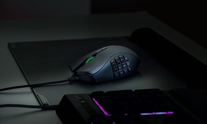 Mouse Razer preto com botões programáveis com fundo preto em um ambiente escuro.