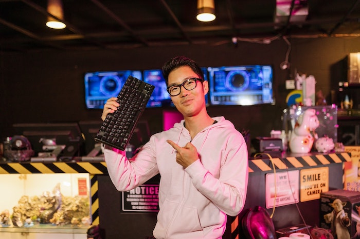 Homem asiático segurando um teclado mecânico em um estúdio de jogos.